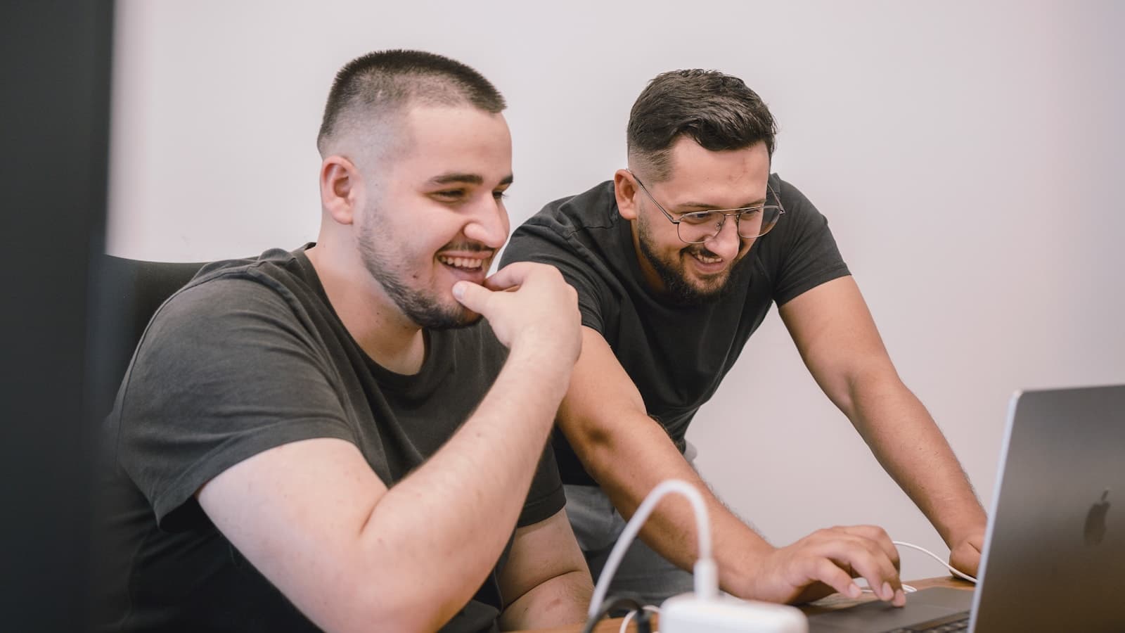 Two coworkers at one laptop while one demonstrates an AI workflow