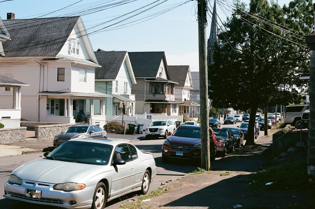 A busy residential street in summer with multiple service vans parked outside homes, illustrating the competitive nature of peak plumbing season