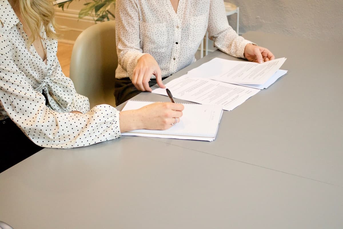 two women signing documents at a desk, finally an inquiry worth the meeting