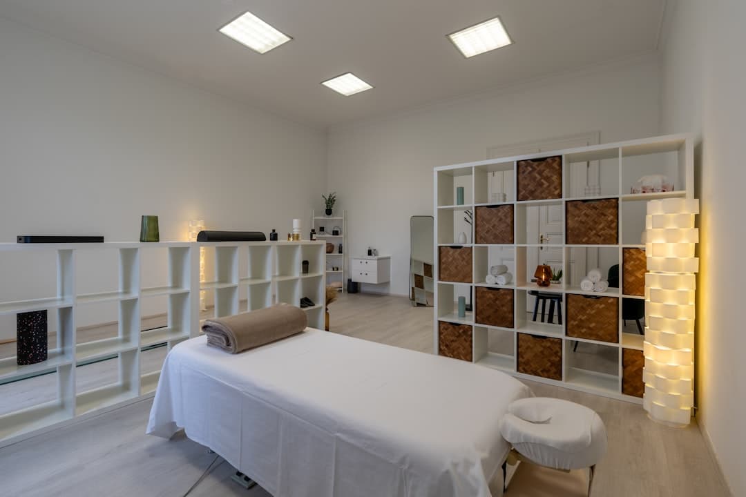 Aesthetic treatment room with draped bed and woven storage, attribution data quietly sitting elsewhere