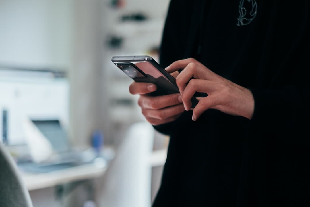 person tapping a smartphone by a laptop, three other brokers got this text too