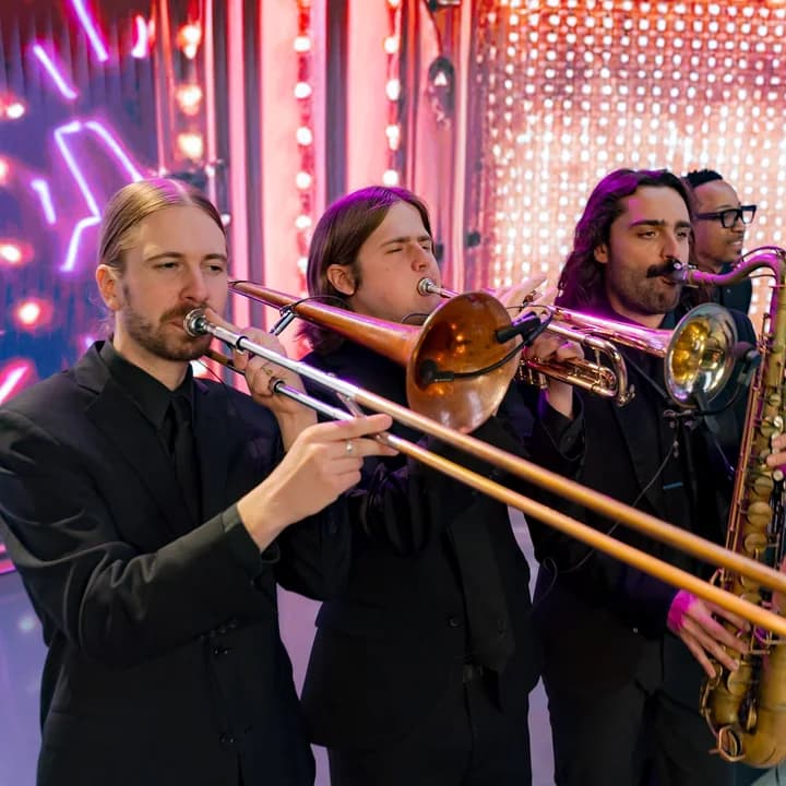 A Jarrell Entertainment horn section performing live on a neon-lit stage