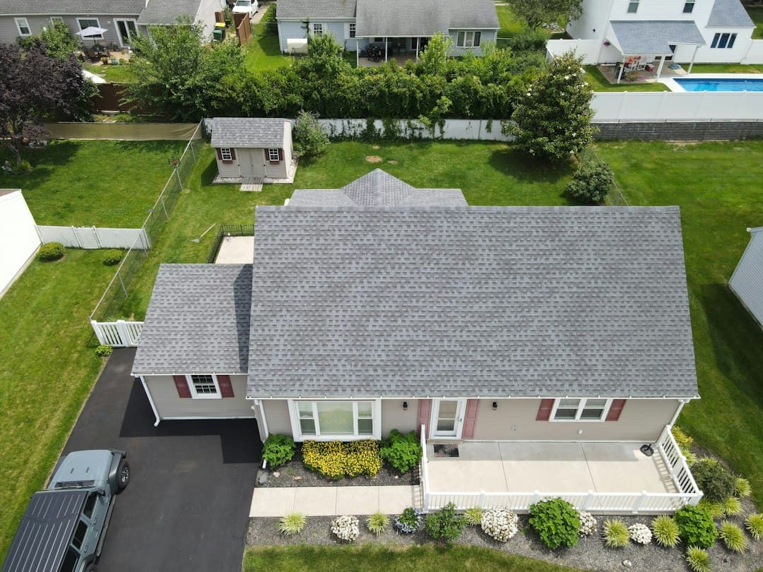 Roofing crew working on a residential shingle roof at midday