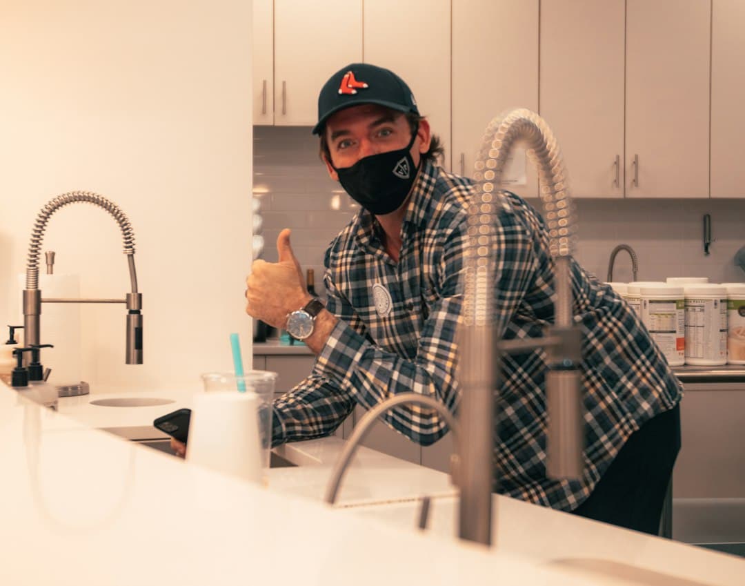 Plumber working under a kitchen sink on a residential repair