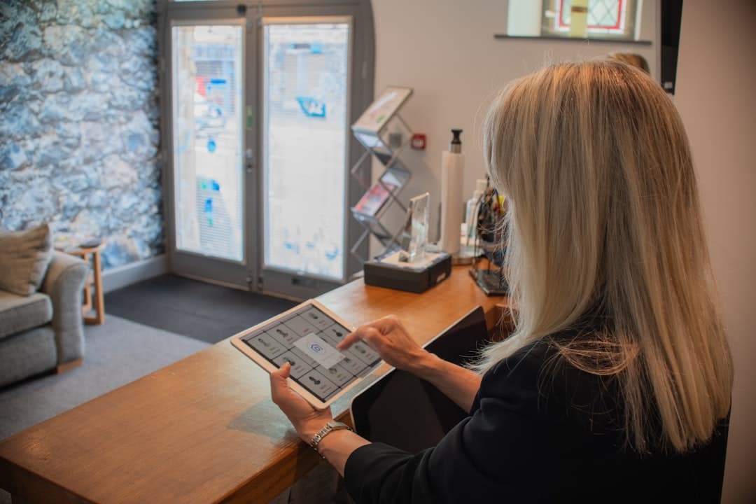 Coral Gables dental coordinator reviewing patient reactivation responses on a tablet at the front desk