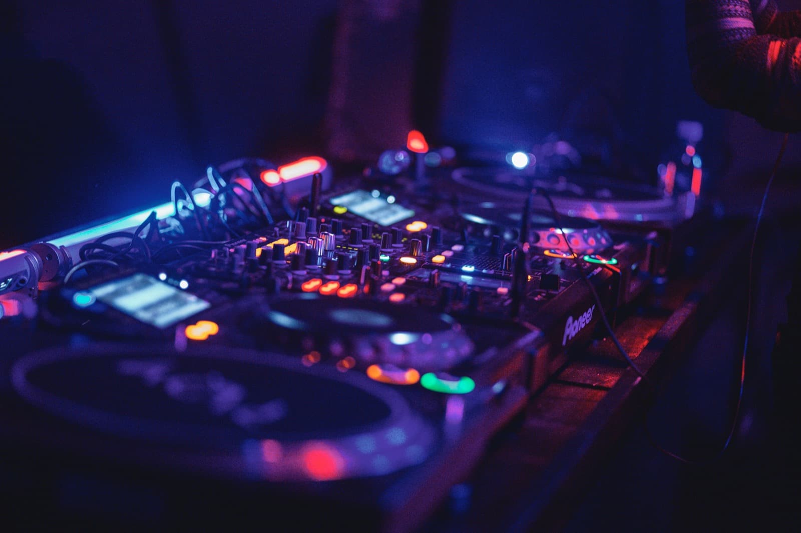 a close-up of a blue-lit DJ audio mixer at a luxury event booth