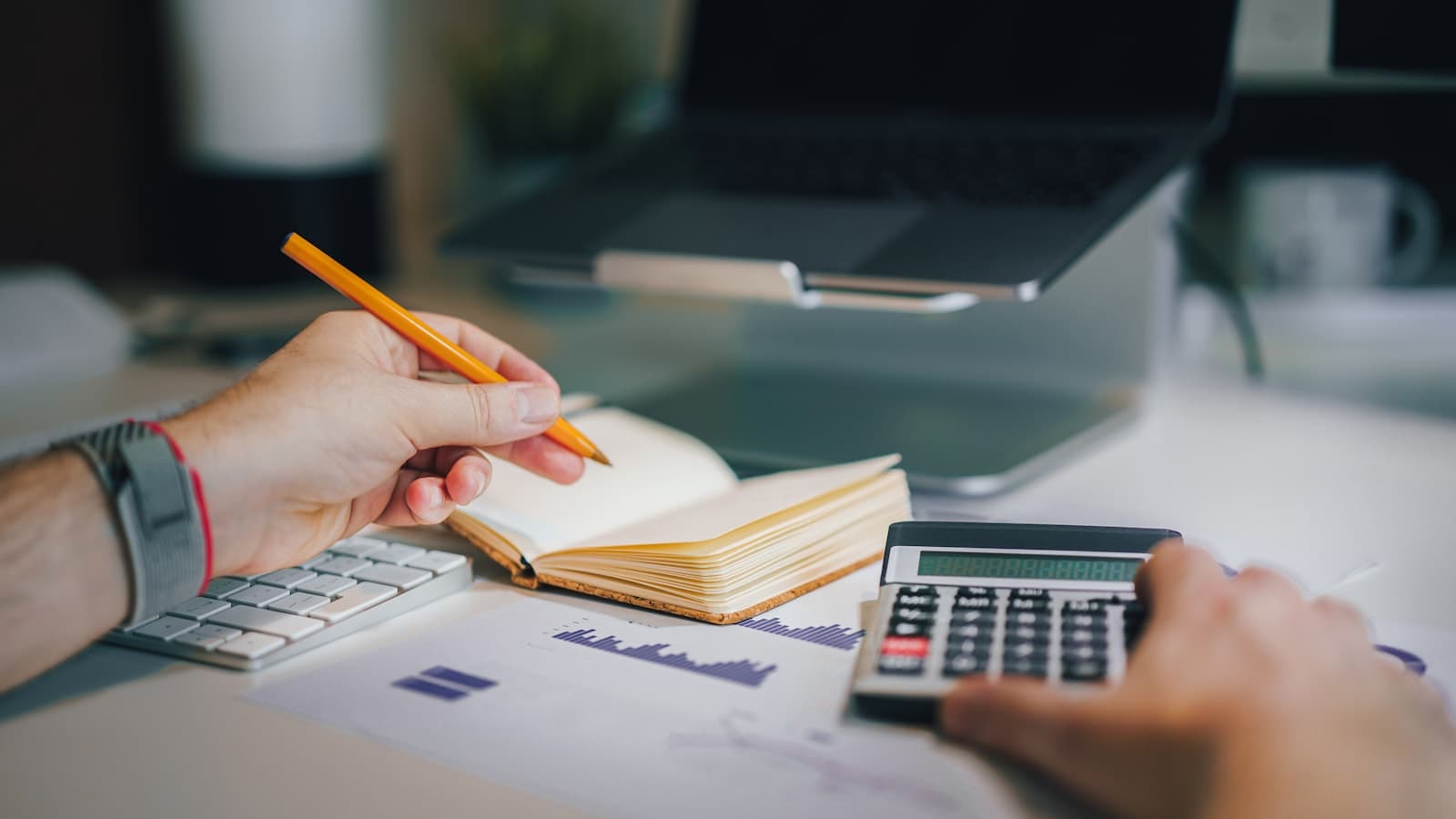 Sales manager drafting an equipment quote with calculator and revenue charts