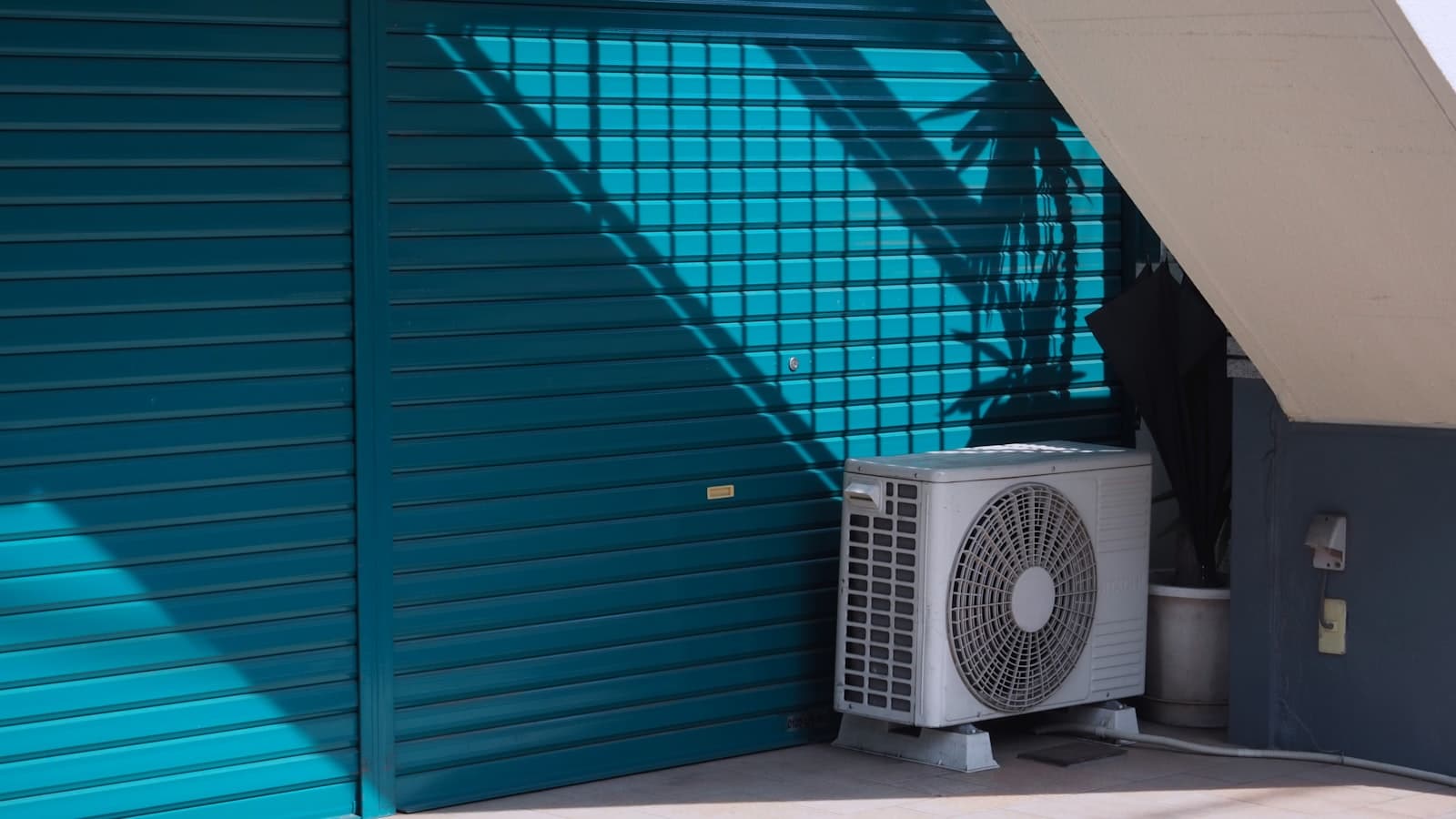 white AC condenser unit beside a teal building wall, fine yesterday, dead at 84 degrees tonight