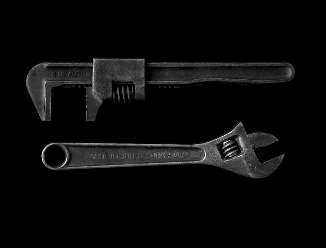 Two pipe wrenches on black background, the after-hours plumbing emergency tool kit