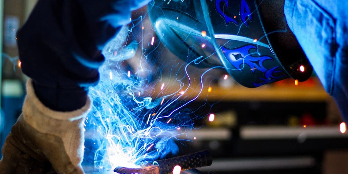 A welder joining a steel part in an equipment fabrication shop