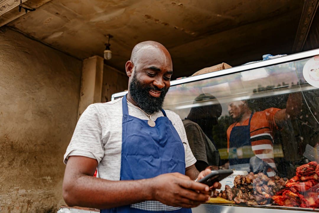 Small business owner at a shop counter checking new Google reviews on a phone