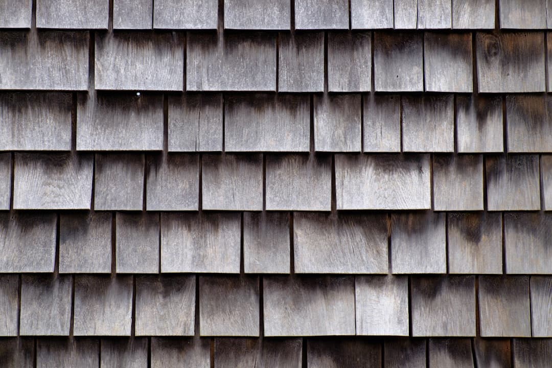 Roofer on a shingle roof reviewing a drone roof inspection report on a tablet