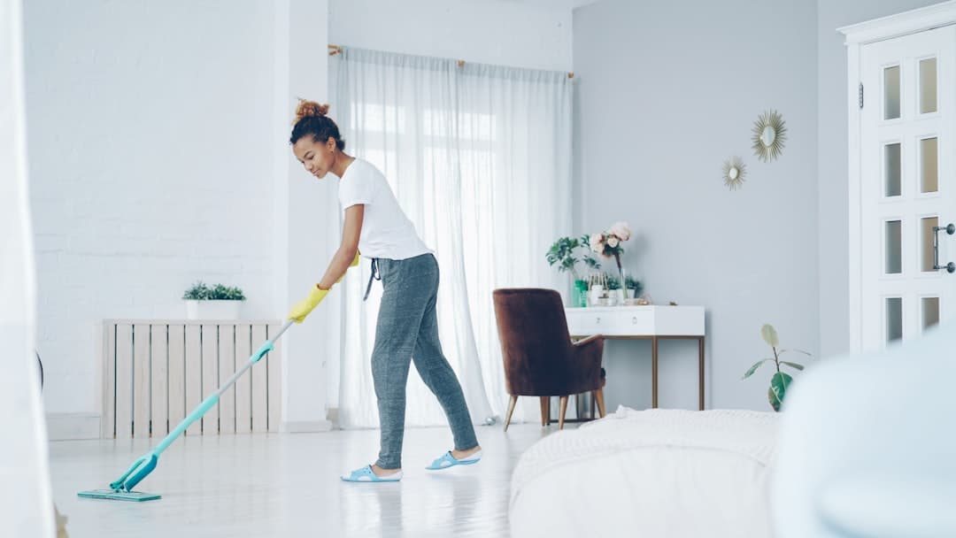 Cleaner resetting a bright vacation rental bedroom with white linens, the turnover nobody sees but everyone Googles