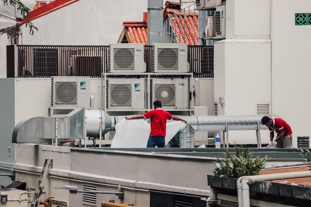 A Houston HVAC technician on a rooftop unit while his phone lights up with incoming calls, the moment HVAC lead generation Houston systems catch the dispatch overflow
