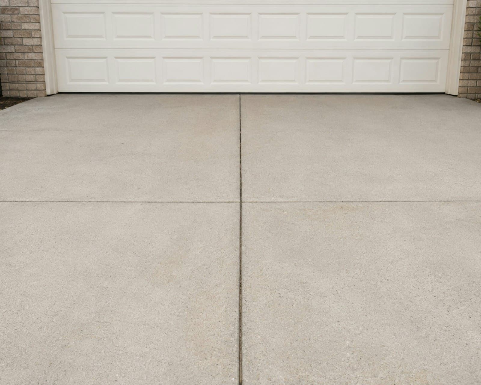 Spotless concrete driveway in front of a white garage, the kind a Miami homeowner books a wash to get