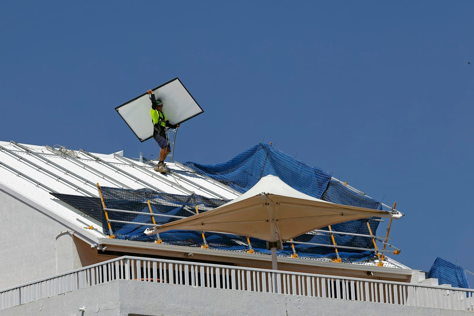 Worker carrying a solar panel across a rooftop, the crew whose work earns the five-star reviews
